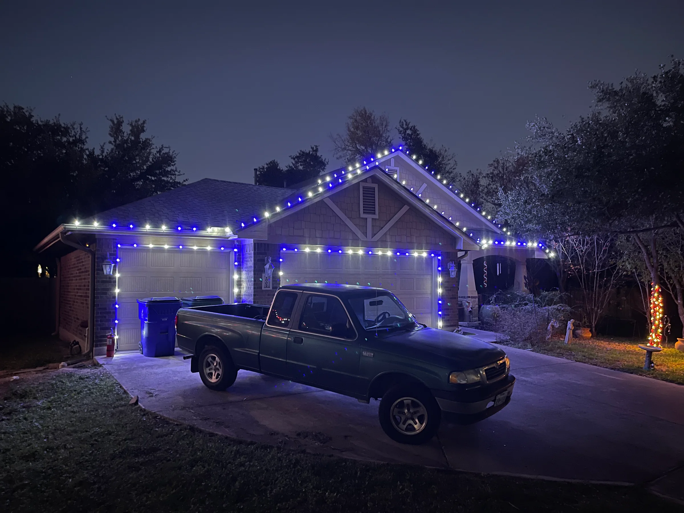 Blue and white Christmas lights outlining a garage-front home