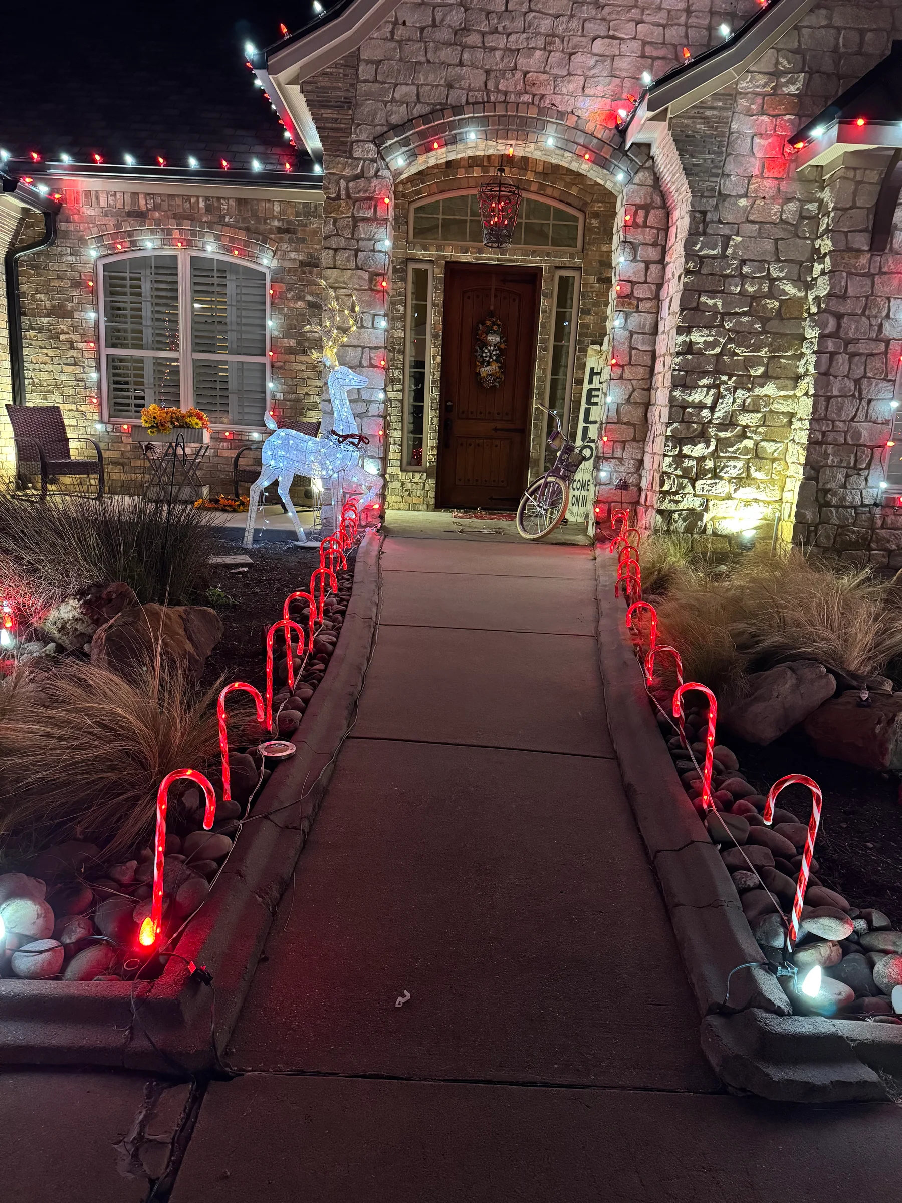Brick home entry and walkway decorated with warm white and red Christmas lights