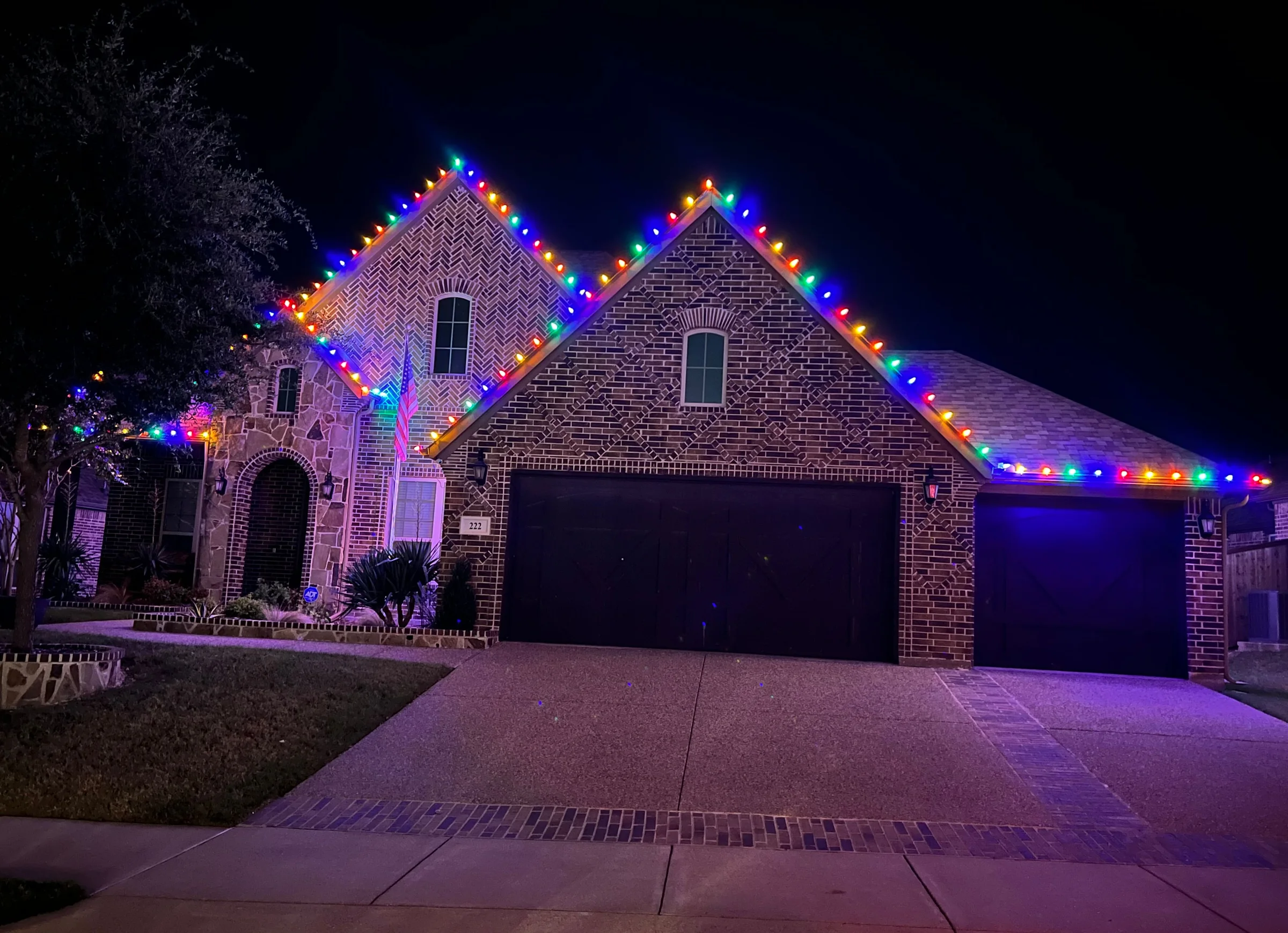 Brick home outlined with large multicolor Christmas lights