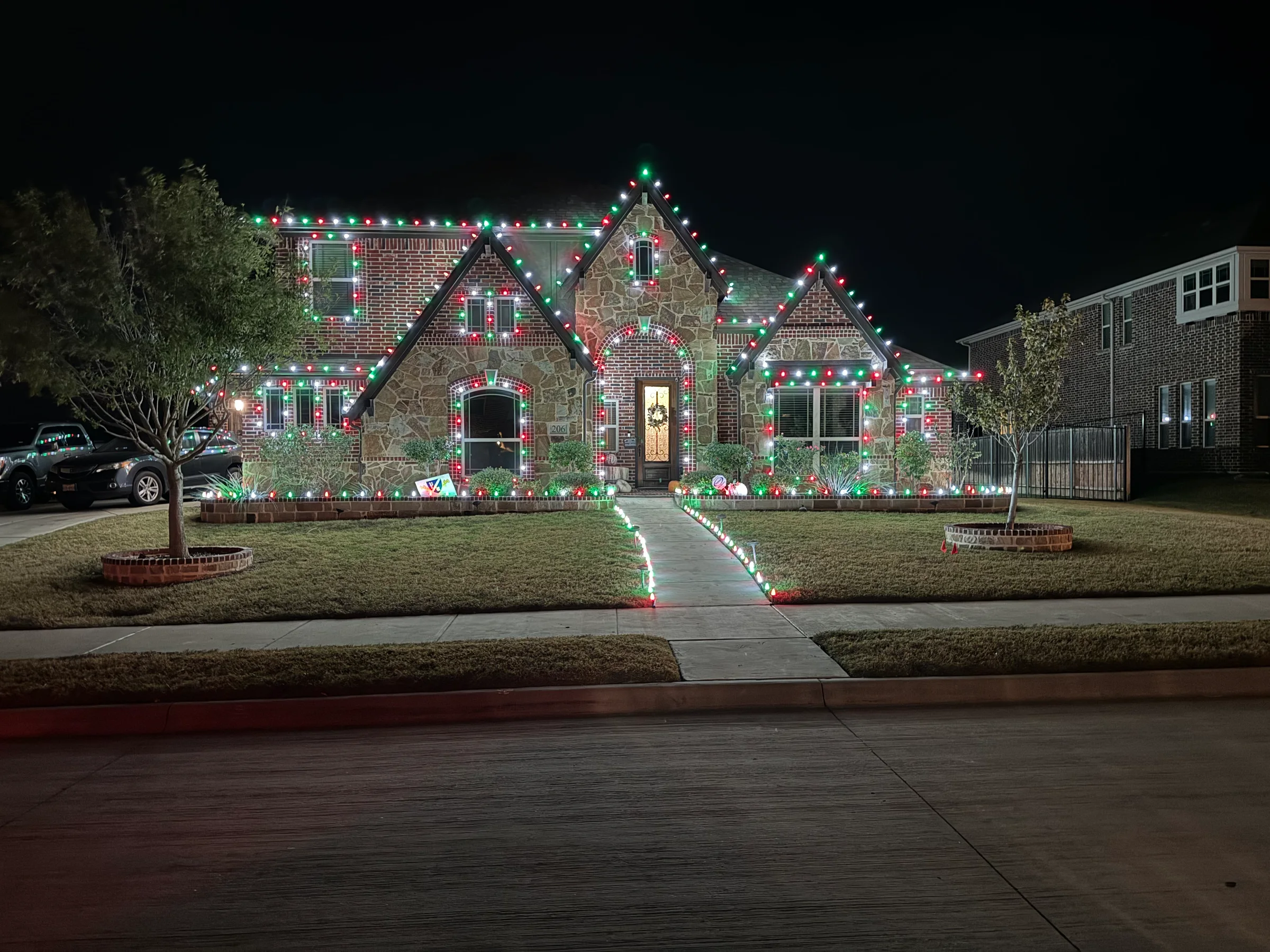 Red, green, and white Christmas lights outlining a home's roofline, windows, and front walk