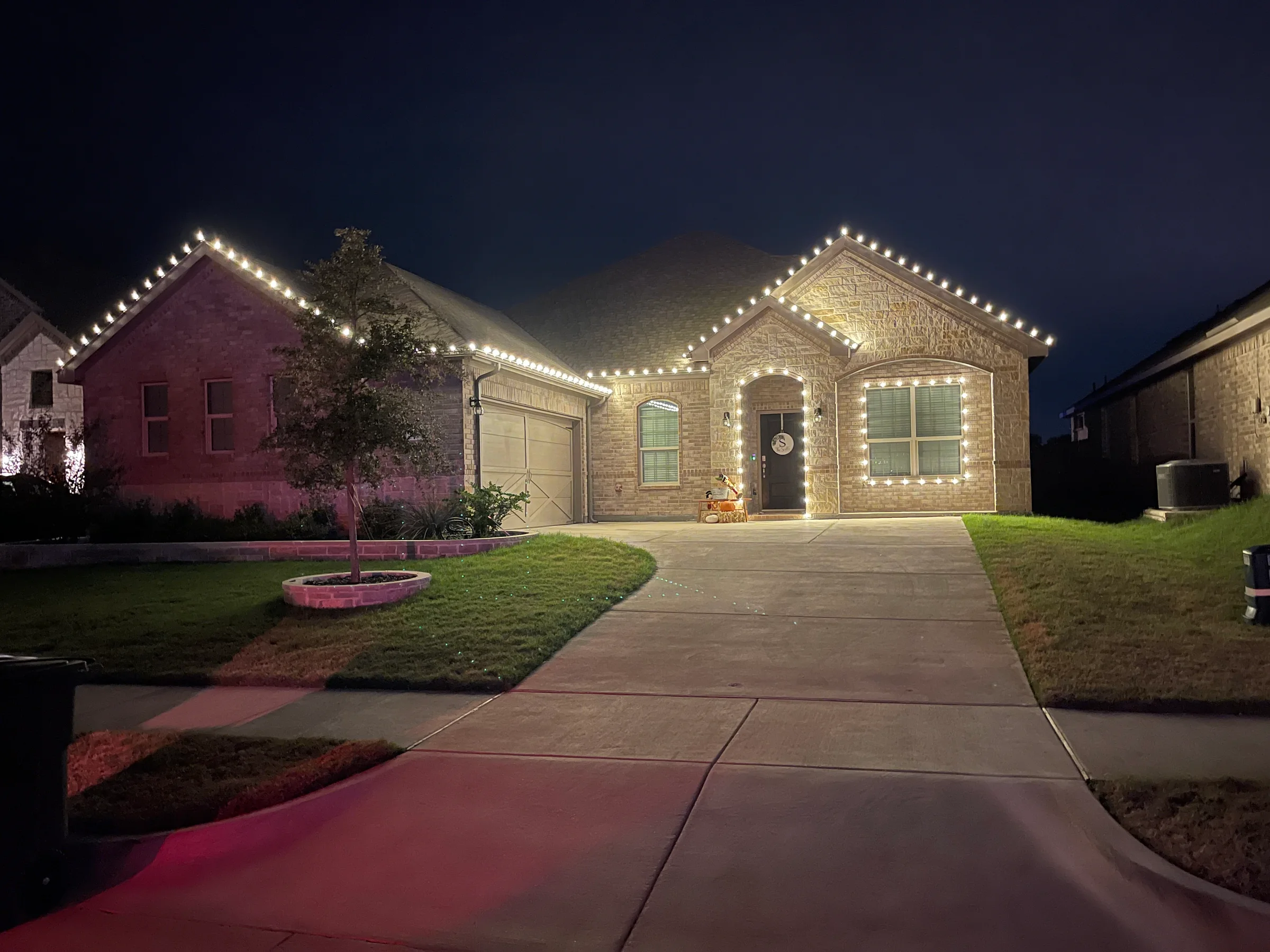 Brick home outlined with warm white roofline lights at night