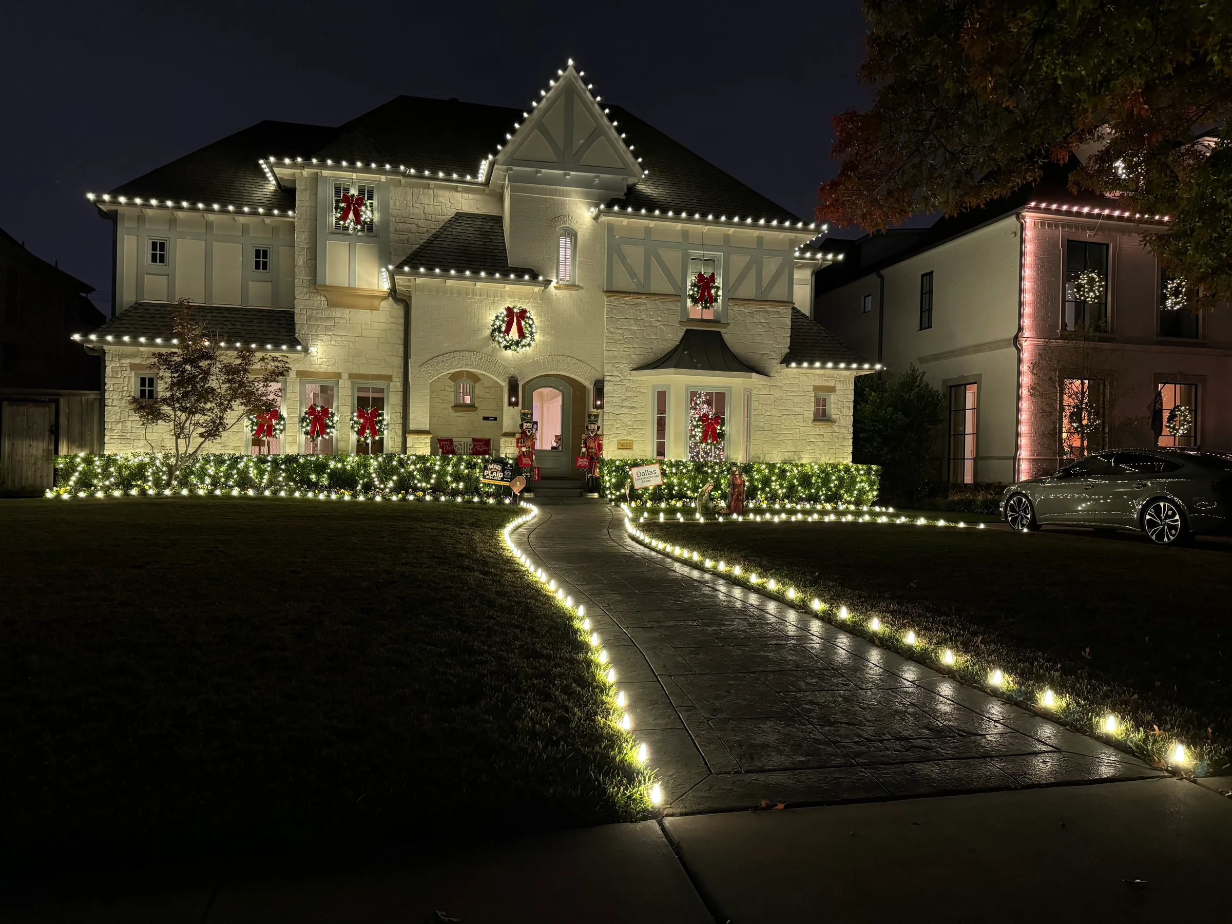 Warm white holiday lighting along a home and front walk