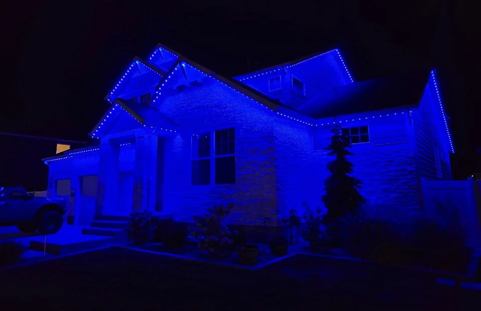 Blue permanent lighting washing a home and tracing its roofline