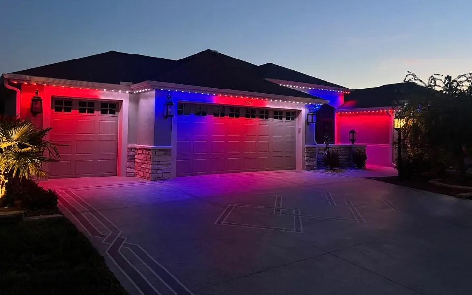 Red and blue permanent lighting across a garage and roofline