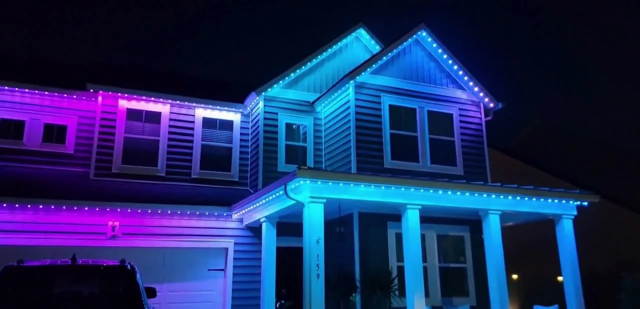 Two-story home displaying blue and magenta permanent roofline lighting
